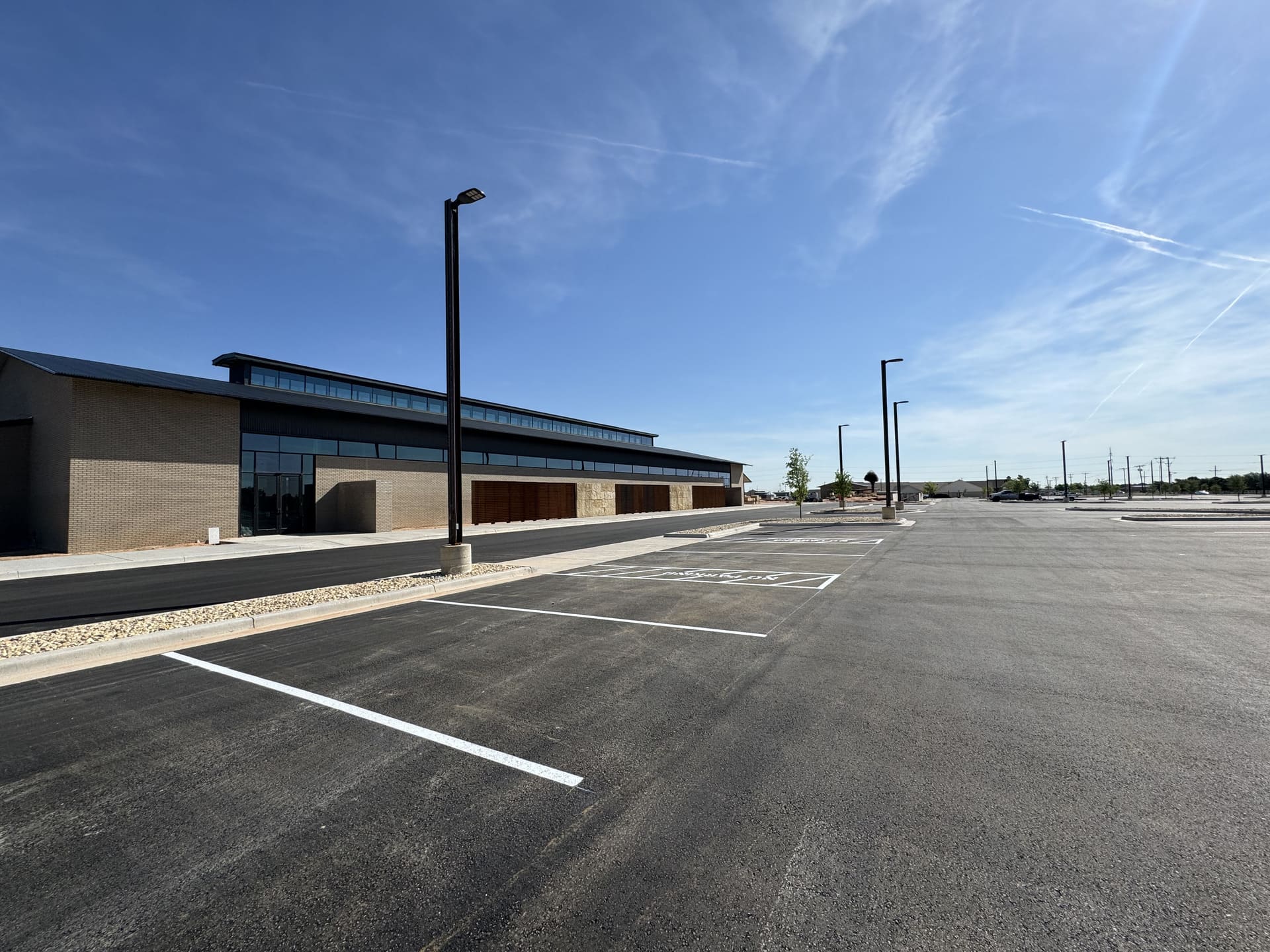 DCIM100MEDIADJI_0081.JPG Freshly paved and striped industrial parking lot under a clear blue sky in Andrews, TX, showcasing Danny's Asphalt Paving's industrial paving work.