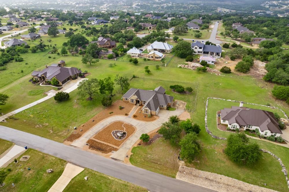 Aerial view of a freshly paved institutional asphalt parking lot with clearly marked white parking lines, directional arrows, and designated parking stalls adjacent to a commercial or educational building.