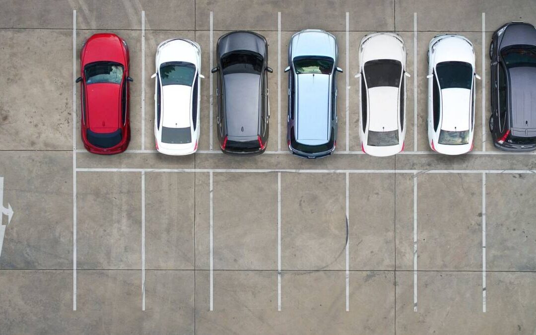 Overhead top-down view of a lined parking lot filled with vehicles during high event season traffic.
